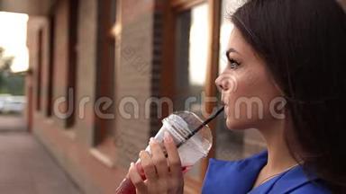 年轻迷人的女人一边喝着清爽的饮料，一边走在城市的街道上。